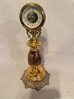 Front view showing entire brass mantel clock and ornate base