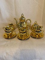 Full tea set front view showing teapot, sugar bowl, creamer, cups and saucers