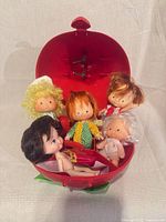 Open strawberry case showing five dolls inside
