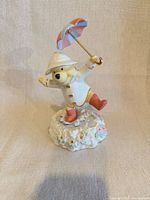 Front view of Winnie the Pooh porcelain music box holding umbrella