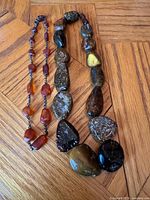 Both necklaces side by side on wood floor