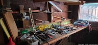 Workbench clutter with axes, saw, hammers, level, cords, blades and hardware