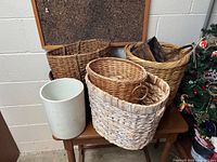 Group of five wicker baskets and one ceramic crock arranged on small table