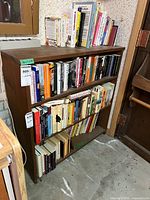 Front view of three-shelf wood bookcase with books (contents excluded)