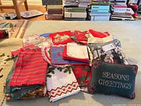 Pile of assorted Christmas linens and two small pillows