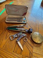 Overview showing Cross case with pen and pencil, group of green Parker/PaperMate pens, enamel knife, whistle, and round Cyprus compact