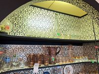 Two shelves showing overall assortment of decanters, pitcher, tumblers and stemware