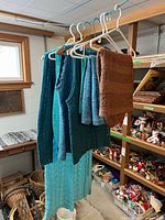 Garments hanging on rack: sweater, vests, skirts, dress visible