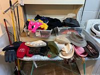 Overall lot showing hats lined on ironing board and bins behind