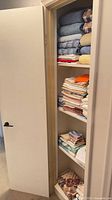 Tall closet with multiple shelves of folded towels, pillowcases and linens