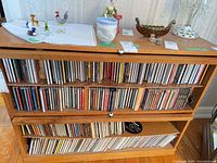 Wide view of three shelves filled with CDs in wooden cabinet