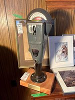 Full view of Duncan parking meter on wooden base with surrounding art for scale