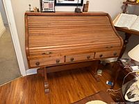 Front view of closed roll-top desk showing overall design and three drawers