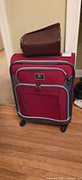 Front view of red Roots carry-on suitcase on spinner wheels