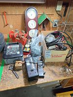 Overview of lot on workbench including charger, barometer, socket set, hardware, cords