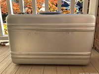 Front view of aluminum suitcase showing ribbed shell and wear