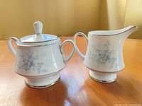 Front view of creamer and lidded sugar bowl showing matching pattern and condition