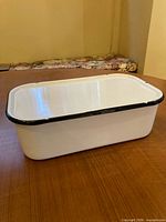 full view of enamel bin with lid on wooden surface