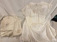 One blouse and skirt displayed; nine additional sets bagged