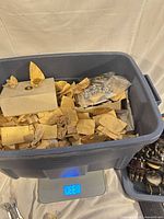 Tote on scale showing contents of brass gears and hardware