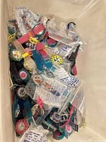 Top view of bin showing large quantity of individually bagged Gitano plastic watches in multiple colors