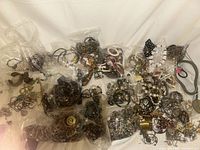 Overview of large quantity of costume jewelry spread out and in bags