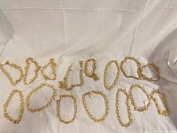 Overview of all ten gold-tone chunky link necklaces laid out on fabric