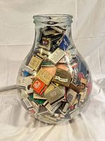 Full view of clear glass vase filled with matchbooks