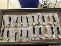 Tray view of ~24 gold-tone women’s quartz watches on bubble wrap