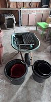 Wheelbarrow with trays inside and two large black buckets in front
