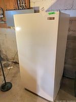 Full view of white Frigidaire upright freezer in basement