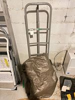 Full view of gray Haussmann hand truck with folded brown tarp resting on base