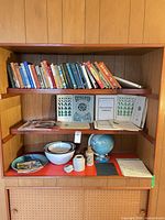 Overall shelf showing books, globes, bowls and stoneware