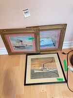 All three framed boat prints leaning against wall