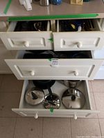 Open cabinet drawers showing cookware lids and pans