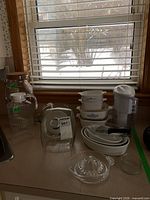 Overall lot showing casseroles, water filter pitcher, beverage dispenser, mixing bowls, storage bowls and juicer