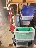 Stack of assorted totes with lids and cleaning tools visible