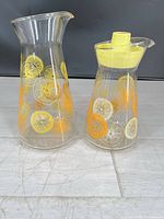 Two Pyrex citrus slice glass carafes side by side