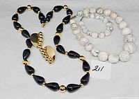 All four jewellery pieces laid out: black/gold Napier necklace, goldtone clip-on earrings, white marbled necklace and bracelet