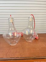 Two clear glass pendant lights with red cords on tabletop