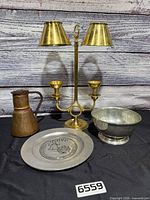 Group shot of brass lamp, copper pitcher, pewter plate, pewter bowl