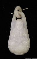 Front view of carved jade Buddha pendant with attached jade bail and size reference pin