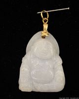 front view of white jade Buddha pendant with gold-tone bail on black background