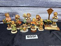 Group view of all Hummel figurines on black cloth