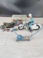 Group shot of all motorcycle collectibles including Bandai RC bike, Benelli model in case, Avon bottle and mini bikes