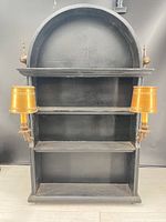 Full view of arched black wood shelf with two gold-tone sconces attached