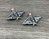 Front view of both cufflinks displaying fly-fish shape and red eyes