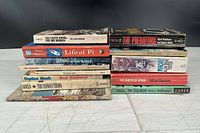 Two stacks of assorted paperback books, spines visible for title identification