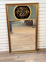 Full view of trumeau mirror showing frame, upper heraldic panel and lower mirror