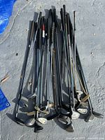 Full lot of mixed golf clubs laid out on ground